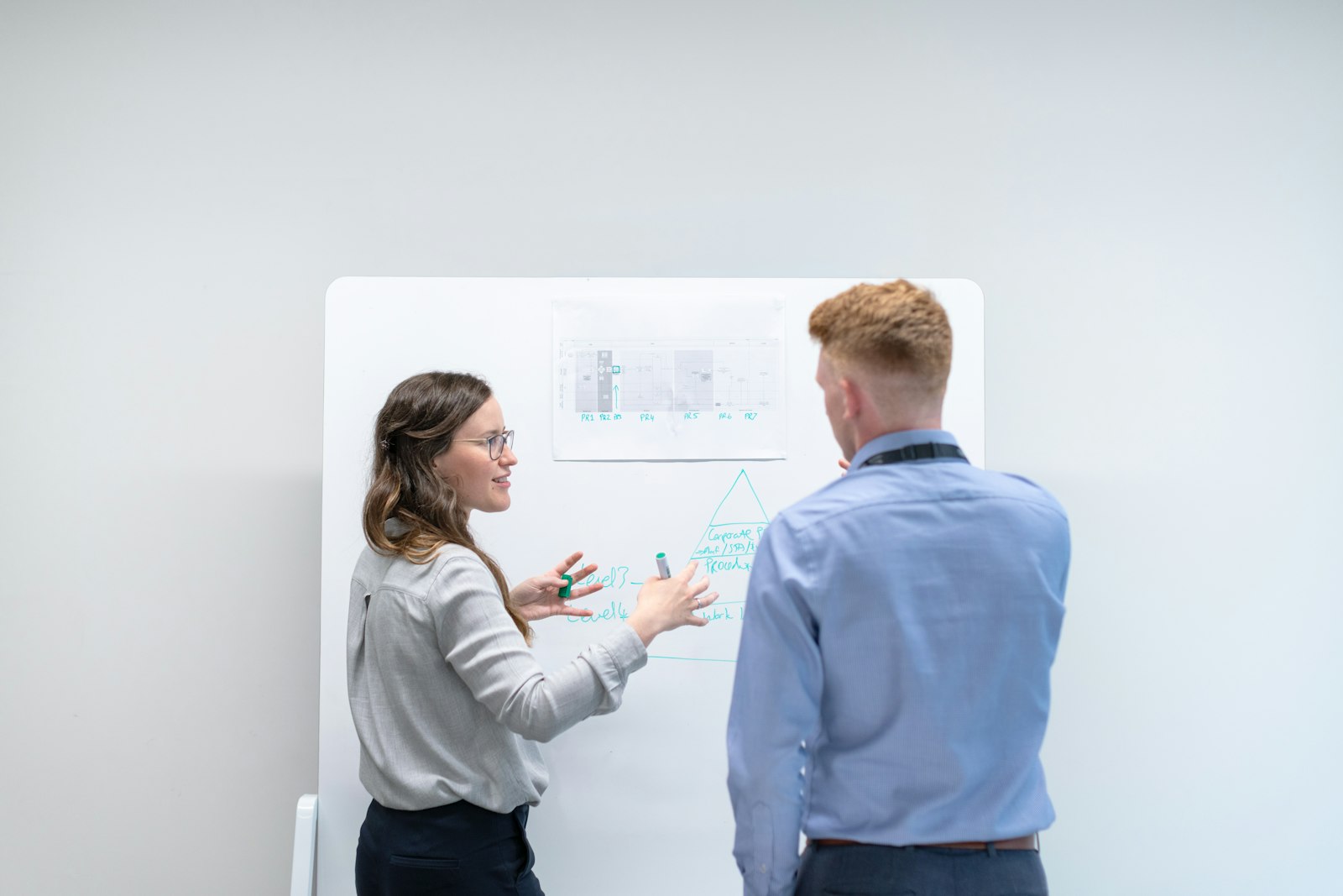 Deux collaborateurs d'un bureau d'études échangeant devant un tableau, branche SYNTEC