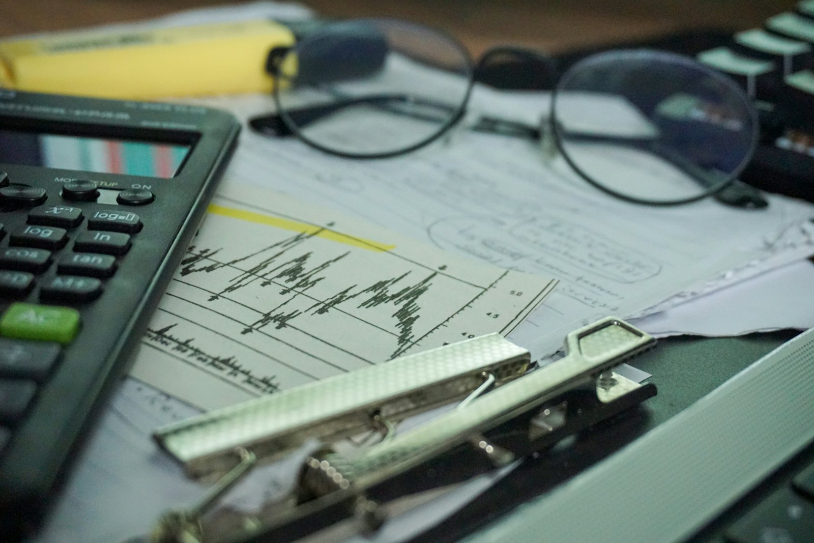 Bureau de direction financière avec calculatrice, documents comptables et lunettes
