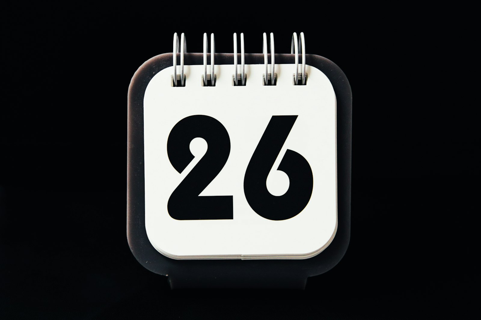Petit calendrier de bureau posé sur un fond sombre, ouvert sur une page portant un chiffre isolé