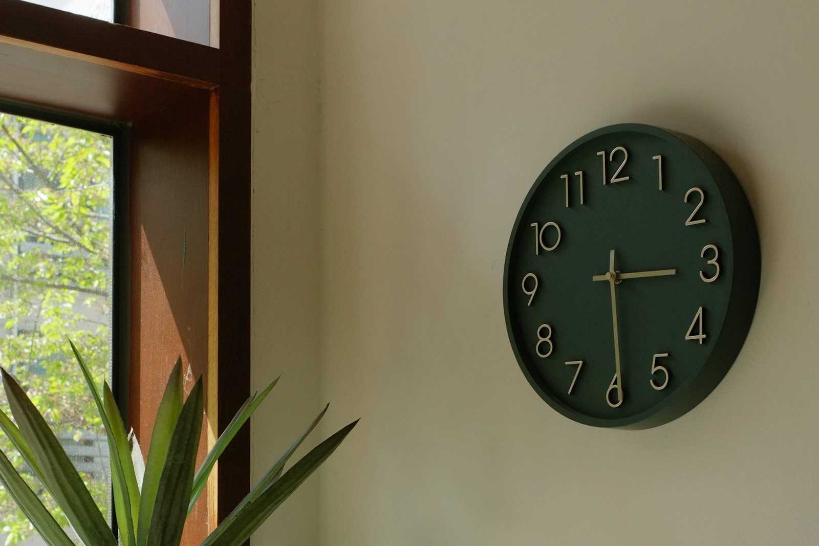 Horloge murale vert foncé dans un bureau clair, près d'une fenêtre