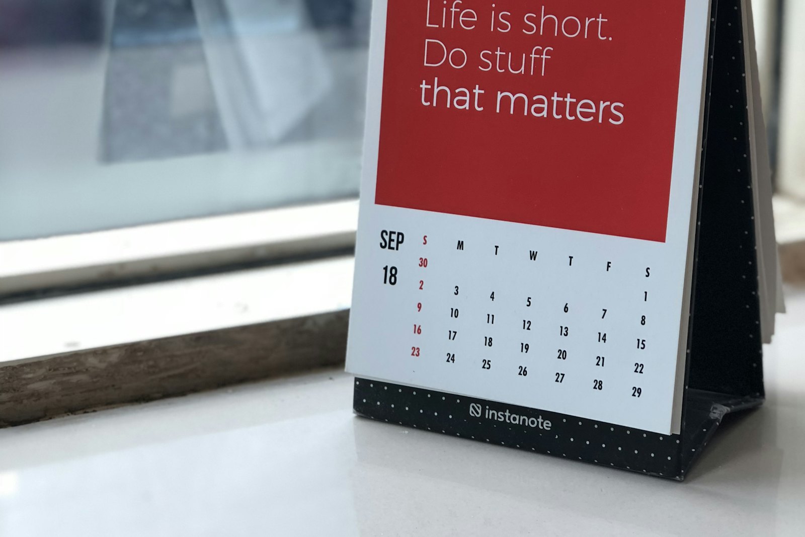 Calendrier de bureau à spirale posé sur un plan de travail clair