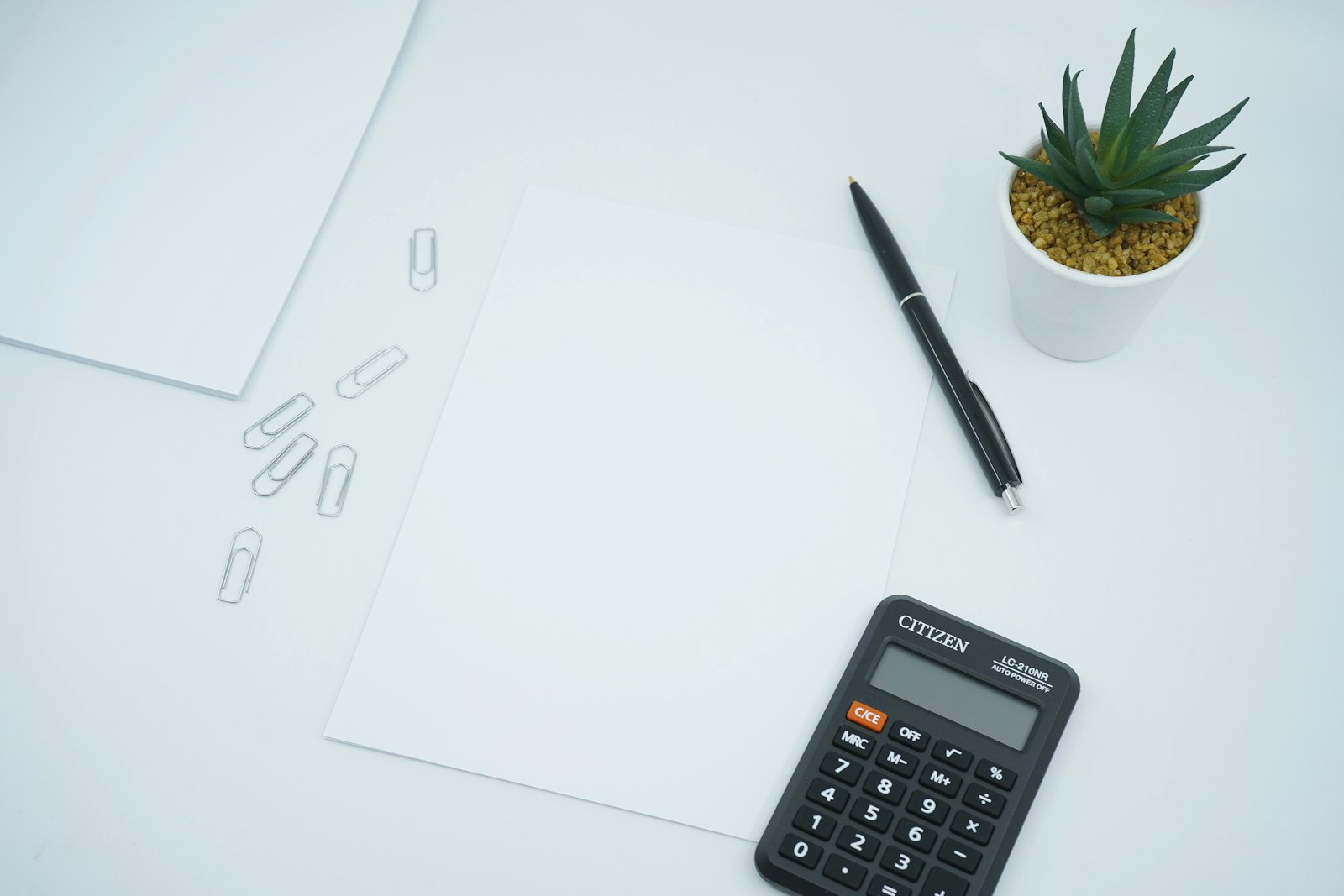 Une calculatrice et un stylo posés sur un tableau de chiffres imprimé