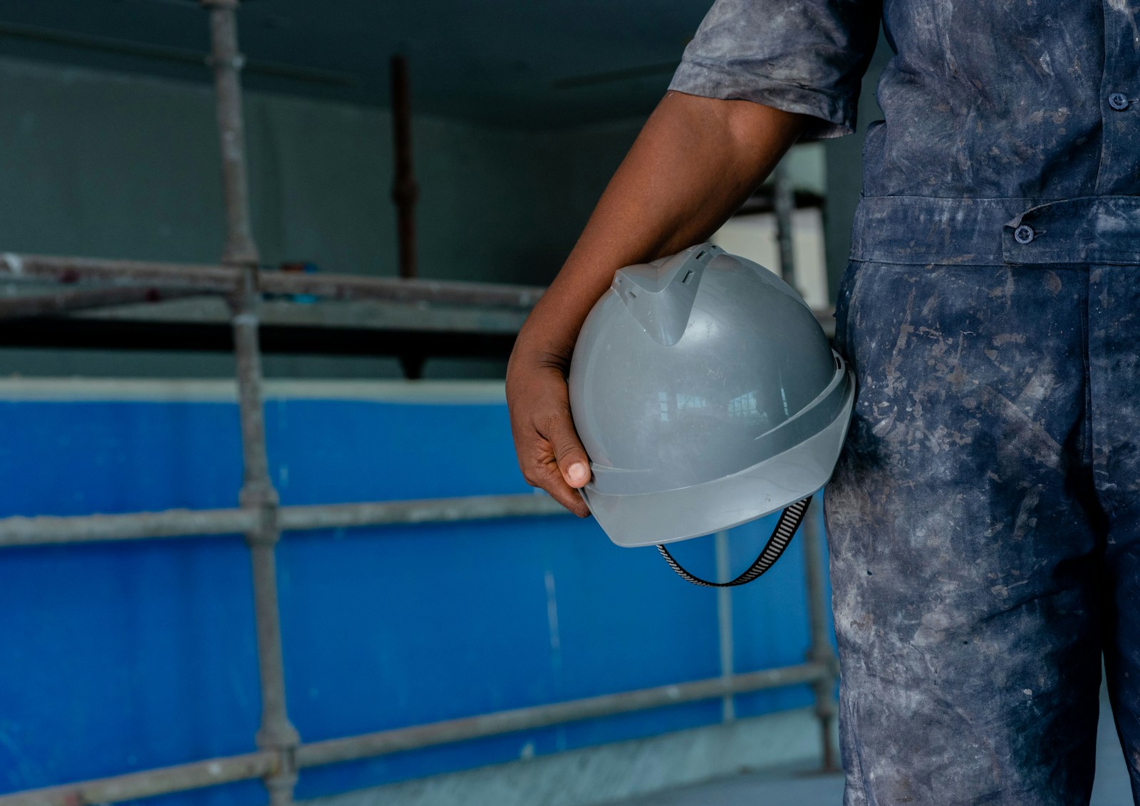 Salarié en bleu de travail tenant son casque de protection, poste exposé aux accidents du travail